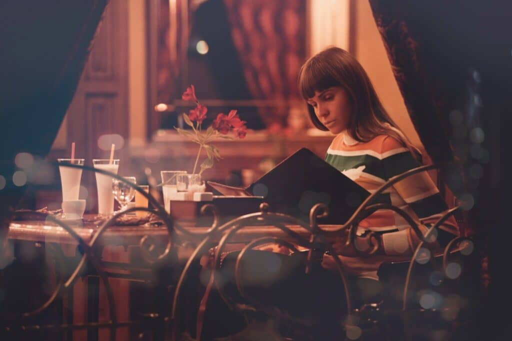 a girl sitting on the chair reading menu of the restaurant