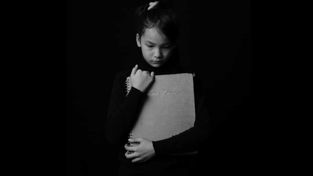 Monochrome Photo of Sad Child hugging a Drawing Pad
